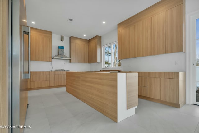 kitchen featuring visible vents, a kitchen island, recessed lighting, modern cabinets, and wall chimney exhaust hood