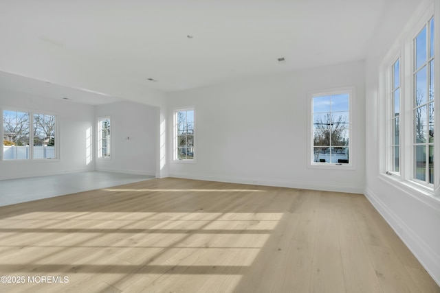 spare room featuring a wealth of natural light, light wood-type flooring, and baseboards