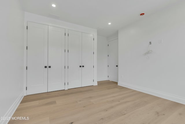 unfurnished bedroom with recessed lighting, baseboards, two closets, and light wood-style flooring