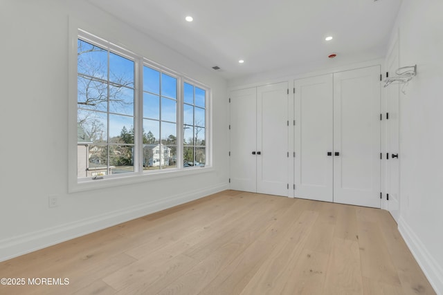 unfurnished bedroom with light wood finished floors, visible vents, two closets, baseboards, and recessed lighting