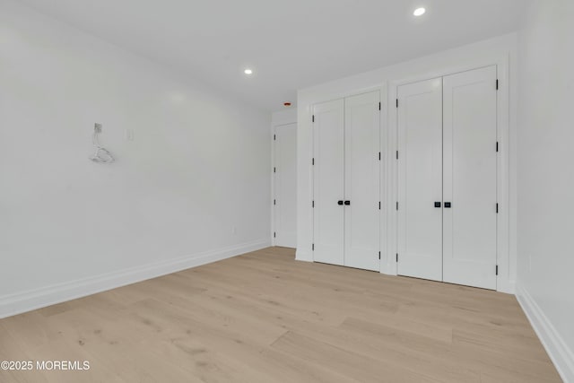 unfurnished bedroom with recessed lighting, light wood-type flooring, multiple closets, and baseboards