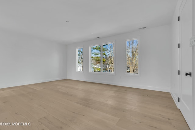 unfurnished room with light wood finished floors, visible vents, and baseboards