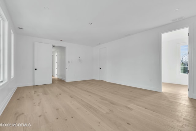 empty room featuring visible vents, baseboards, and light wood-style floors