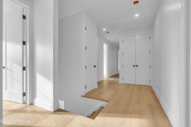 hallway featuring recessed lighting, baseboards, attic access, and light wood-style flooring