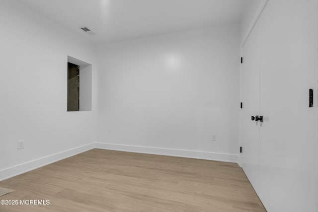 unfurnished room with visible vents, light wood-style flooring, and baseboards