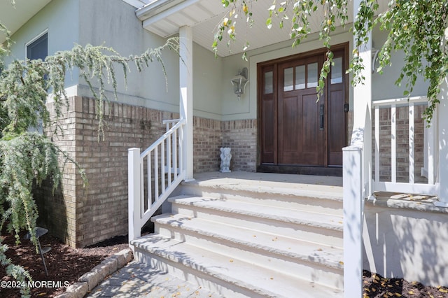 entrance to property featuring covered porch and brick siding