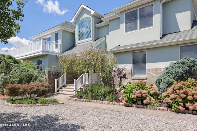 view of front of house featuring a shingled roof, brick siding, and stucco siding