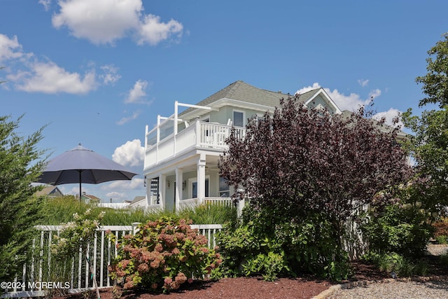 view of side of home with fence and a balcony