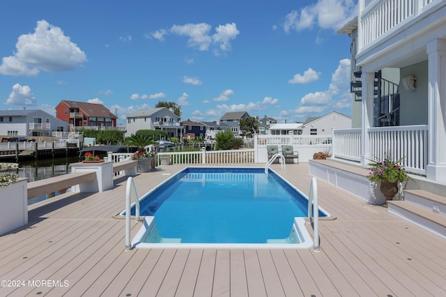 view of pool featuring a deck with water view, a residential view, and a fenced in pool