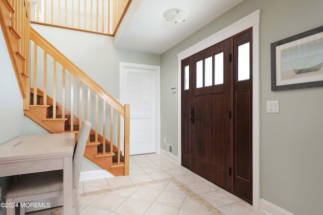 entrance foyer featuring light tile patterned floors, stairway, and baseboards