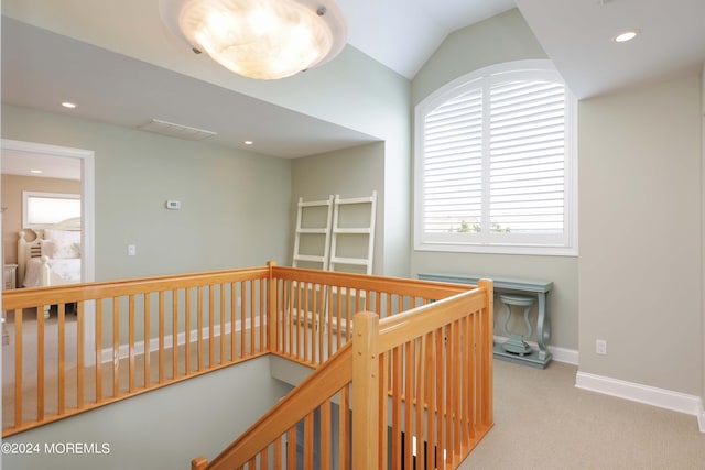 hallway with visible vents, light colored carpet, an upstairs landing, and a healthy amount of sunlight