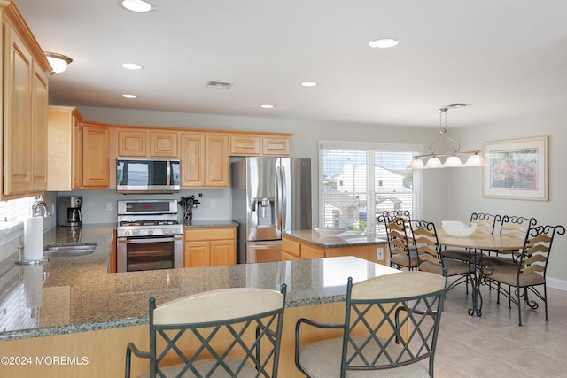 kitchen featuring visible vents, appliances with stainless steel finishes, light stone countertops, pendant lighting, and a sink