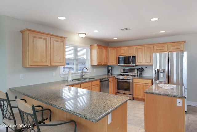 kitchen with stone counters, stainless steel appliances, a sink, visible vents, and a center island