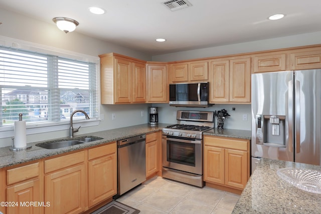 kitchen with light tile patterned floors, visible vents, appliances with stainless steel finishes, stone countertops, and a sink