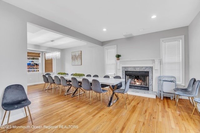 dining room with hardwood / wood-style flooring, a premium fireplace, and a chandelier