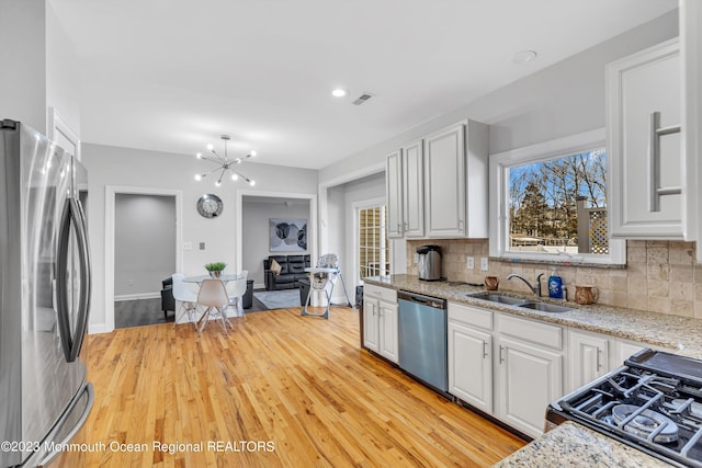 kitchen featuring sink, white cabinetry, appliances with stainless steel finishes, light stone countertops, and backsplash