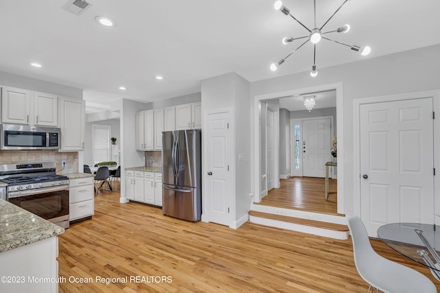 kitchen with tasteful backsplash, stainless steel appliances, light hardwood / wood-style floors, and white cabinets