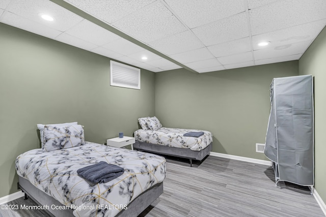 bedroom with a paneled ceiling and light hardwood / wood-style floors