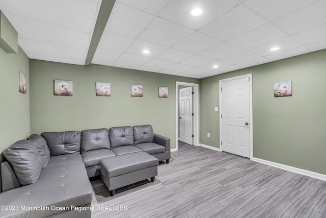 living room with light hardwood / wood-style floors and a drop ceiling