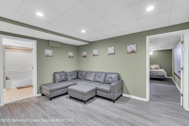 living room featuring a paneled ceiling and light hardwood / wood-style flooring