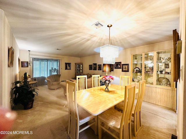 carpeted dining room featuring an inviting chandelier