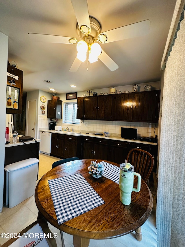 kitchen featuring decorative backsplash, dark brown cabinets, white dishwasher, ceiling fan, and light tile patterned floors