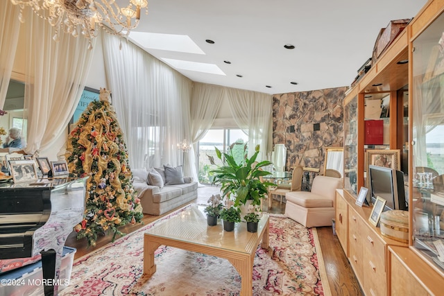 living area featuring a skylight, a notable chandelier, and wood finished floors