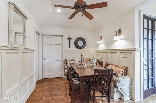 dining area with a wainscoted wall, dark wood-style flooring, a ceiling fan, and a decorative wall