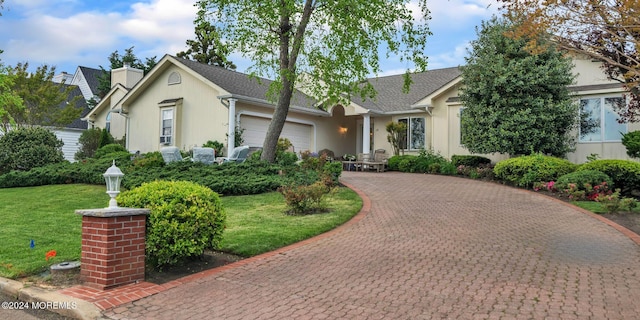 view of front of home with a garage, a front lawn, decorative driveway, and stucco siding