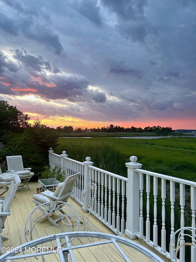 deck at dusk featuring a rural view