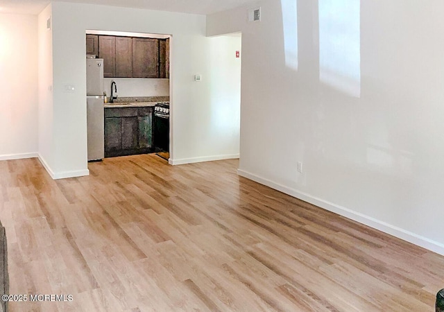 unfurnished living room with sink and light hardwood / wood-style flooring