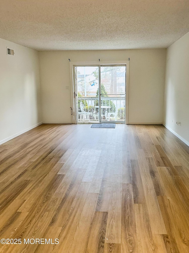 spare room featuring light wood-type flooring and a textured ceiling