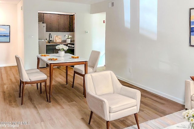 dining space with sink and light wood-type flooring