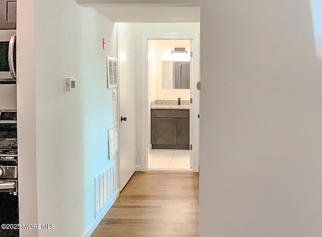 corridor featuring sink and light hardwood / wood-style flooring