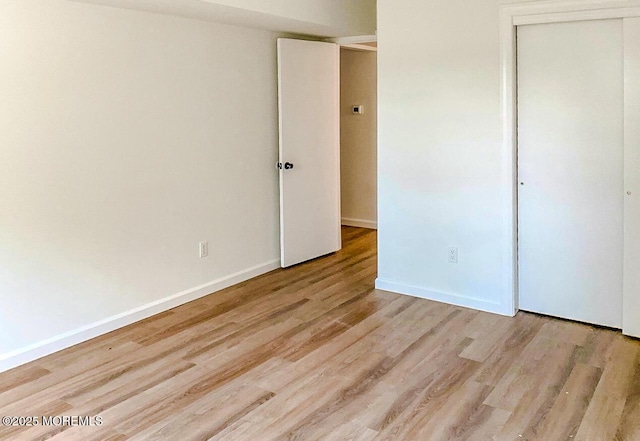 unfurnished bedroom with light wood-type flooring and a closet