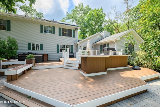 rear view of house with a hot tub and a wooden deck