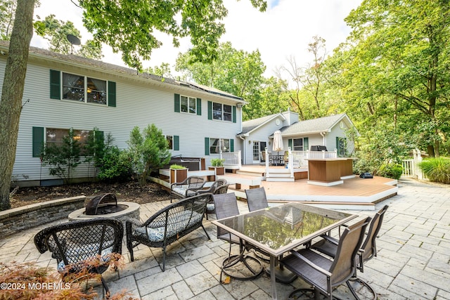 back of house featuring an outdoor fire pit, a patio area, outdoor dining space, and a wooden deck