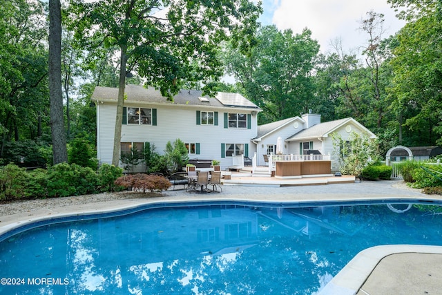 rear view of house featuring an outdoor pool, a patio, and a wooden deck