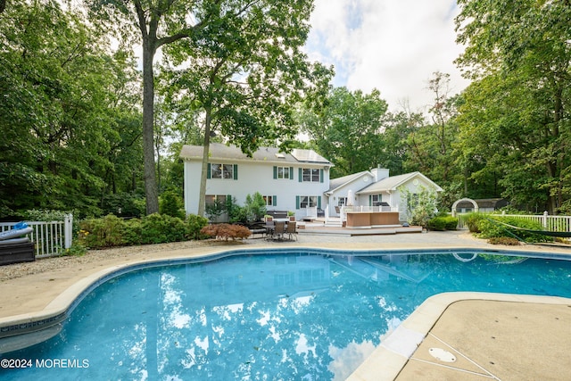 pool with a patio area, fence, and a wooden deck