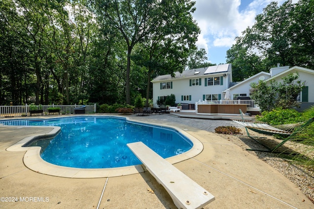 view of swimming pool featuring a fenced in pool, a patio, fence, a deck, and a diving board