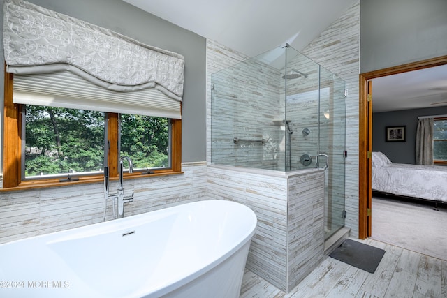 ensuite bathroom with tile walls, lofted ceiling, a freestanding bath, a stall shower, and connected bathroom