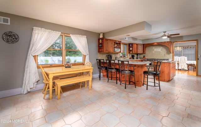 kitchen featuring visible vents, brown cabinetry, decorative backsplash, a kitchen bar, and open shelves