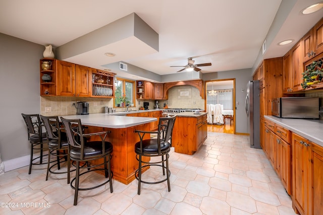 kitchen with open shelves, brown cabinetry, a peninsula, and freestanding refrigerator