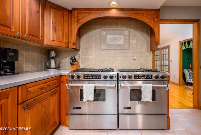 kitchen with brown cabinets, stainless steel gas stove, and light tile patterned floors