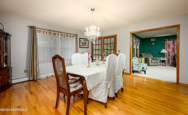 dining space with a chandelier, light wood finished floors, and baseboard heating