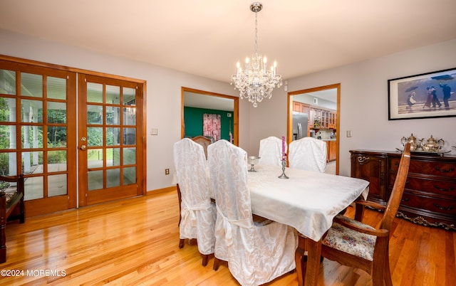 dining space featuring french doors, a notable chandelier, and light wood-style flooring