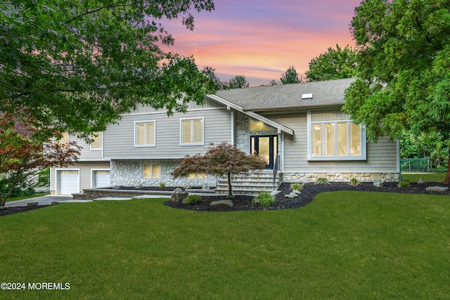 raised ranch featuring a lawn and a garage