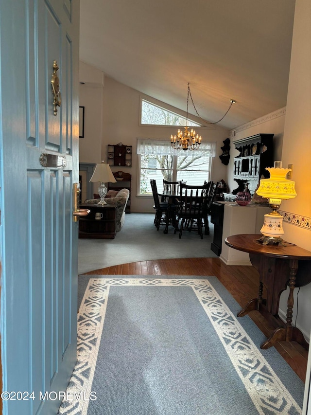 dining area with hardwood / wood-style flooring, an inviting chandelier, and lofted ceiling