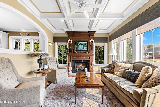 living room featuring coffered ceiling, plenty of natural light, crown molding, and a high end fireplace