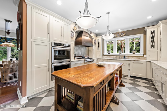 kitchen with backsplash, light hardwood / wood-style flooring, custom range hood, stainless steel appliances, and white cabinets